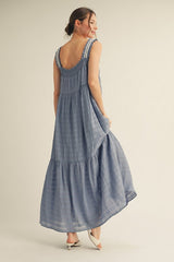 woman wearing a light blue sleeveless maxi dress with tiered hem and textured fabric, shown from the back