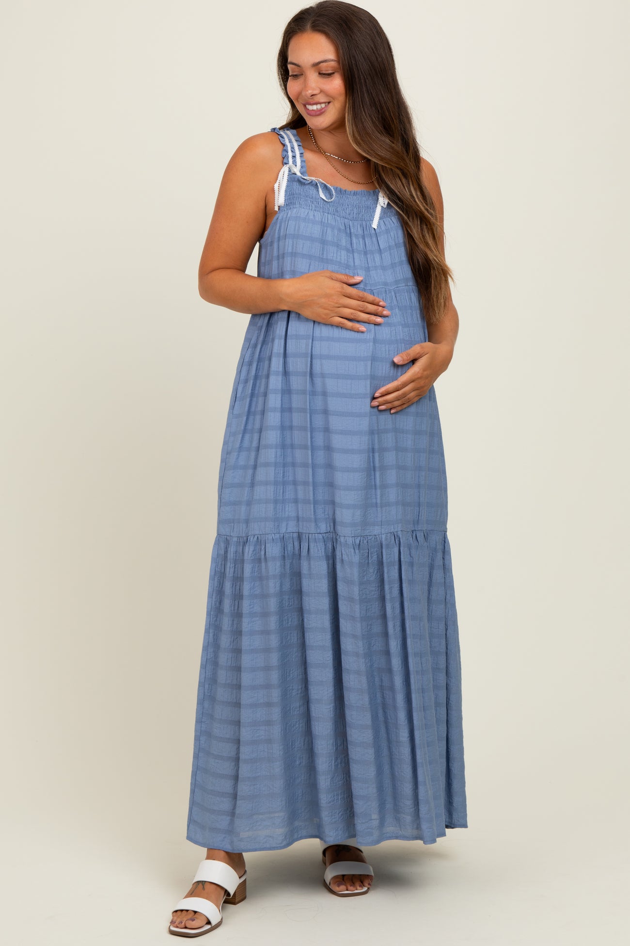 woman wearing a light blue striped maternity maxi dress and holding her baby bump