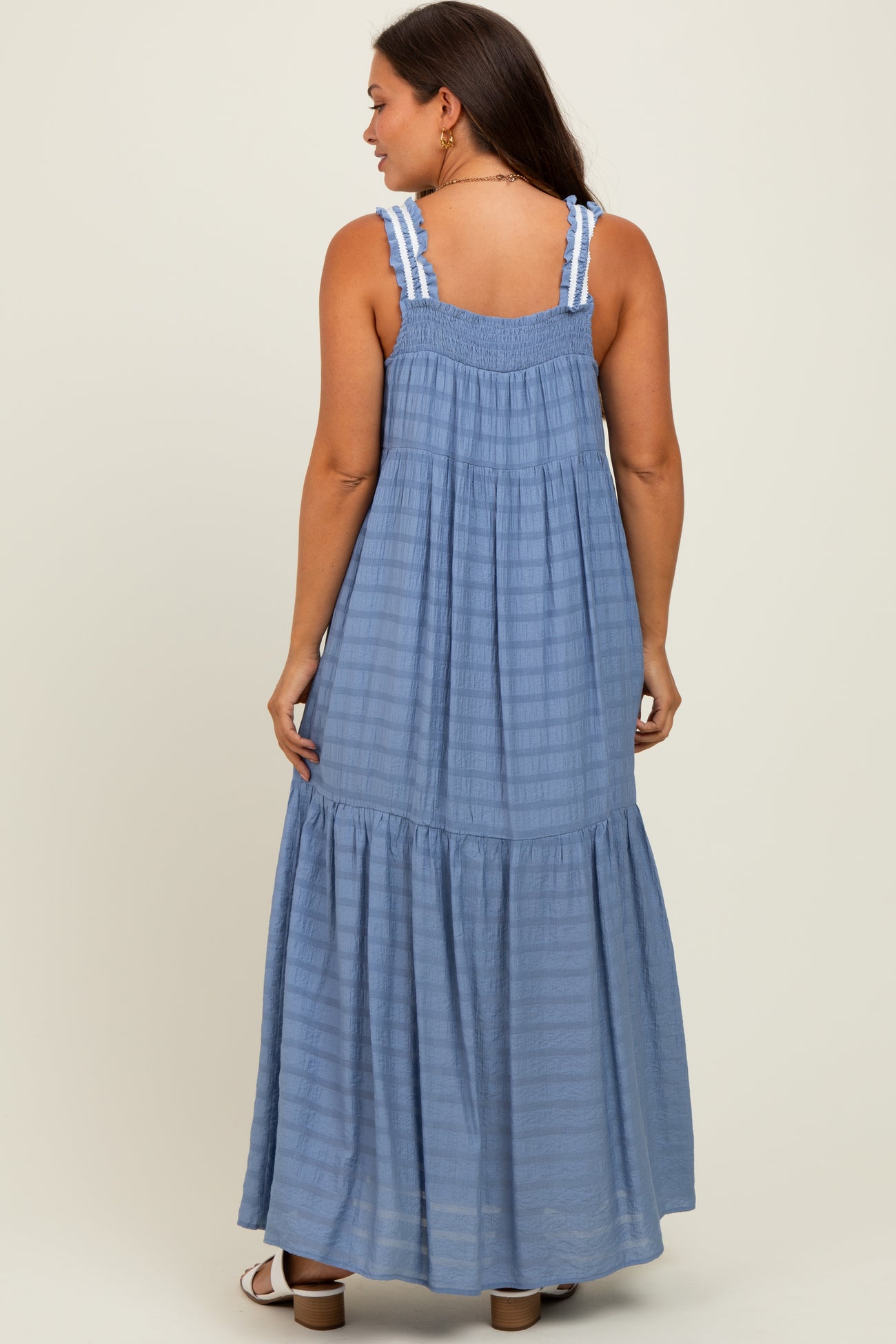 woman wearing a light blue maternity maxi dress with a smocked back and ruffled hem.