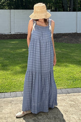 woman wearing a blue striped maxi dress with adjustable straps and a tiered skirt, standing in a grassy outdoor setting