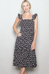 woman wearing a navy blue floral midi dress with ruffled straps and a tiered skirt