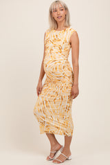 woman wearing a yellow and white tie-dye maternity dress with ruching and a visible baby bump