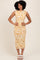 woman wearing a fitted midi dress with a yellow abstract print and ruching details, standing against a neutral background
