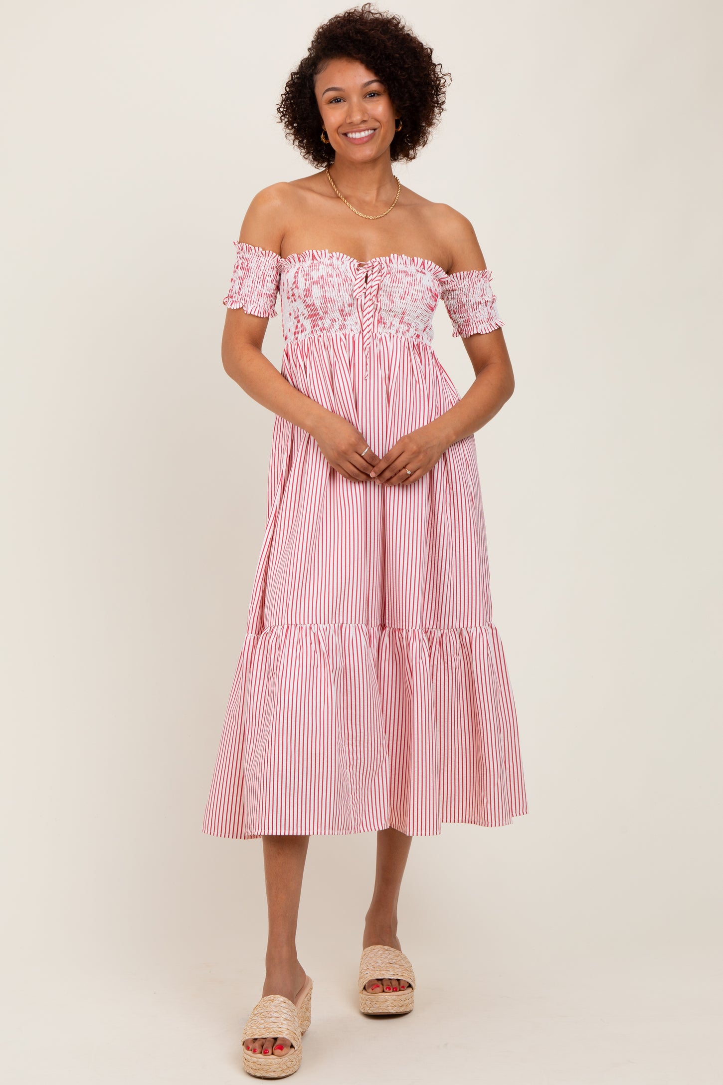 woman wearing a pink and white striped off-shoulder midi dress with floral details and a tiered hem