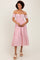 woman wearing a pink and white striped off-shoulder midi dress with floral details and a tiered hem