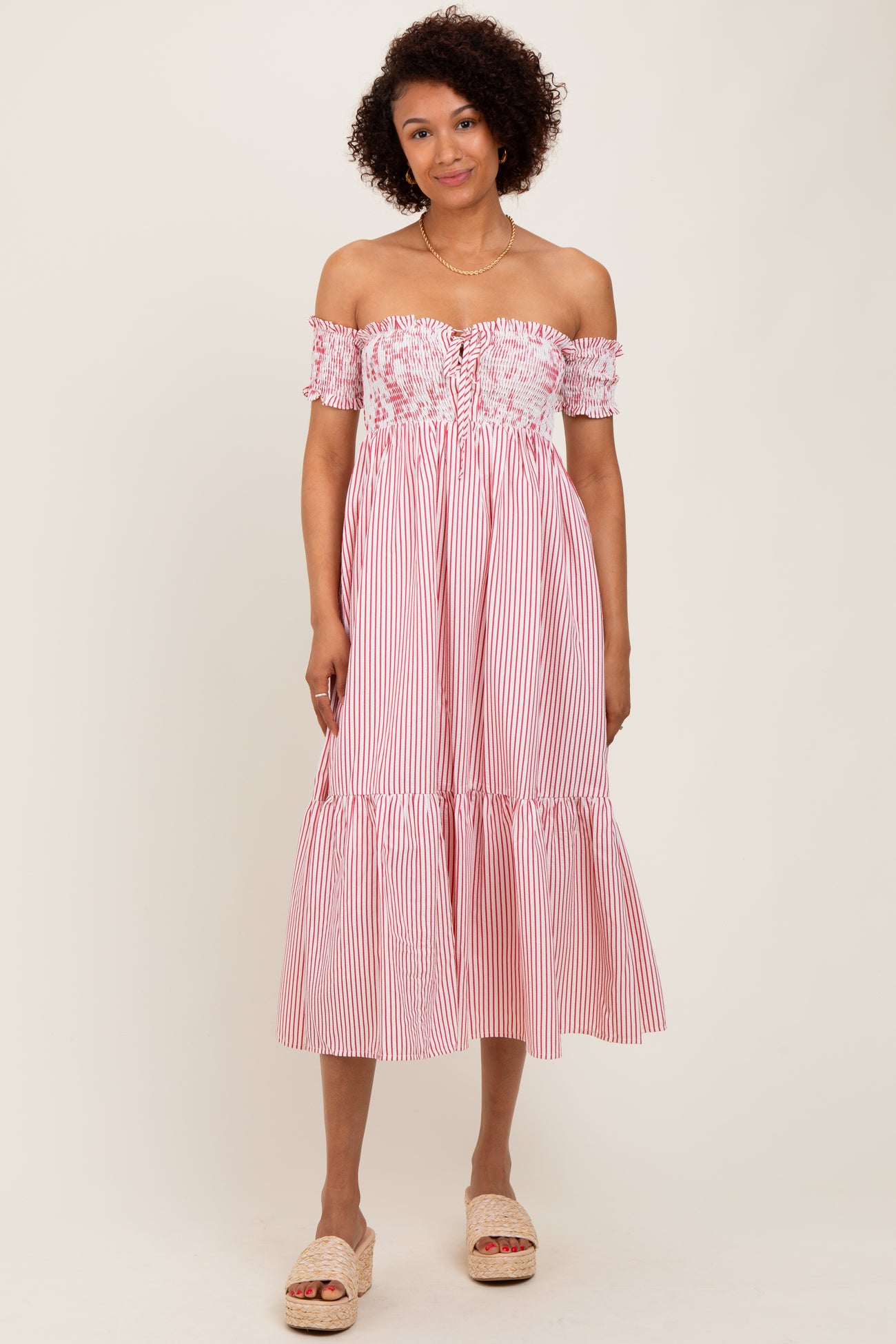 woman wearing a red and white striped off-the-shoulder midi dress with a ruffled hem and floral bodice details