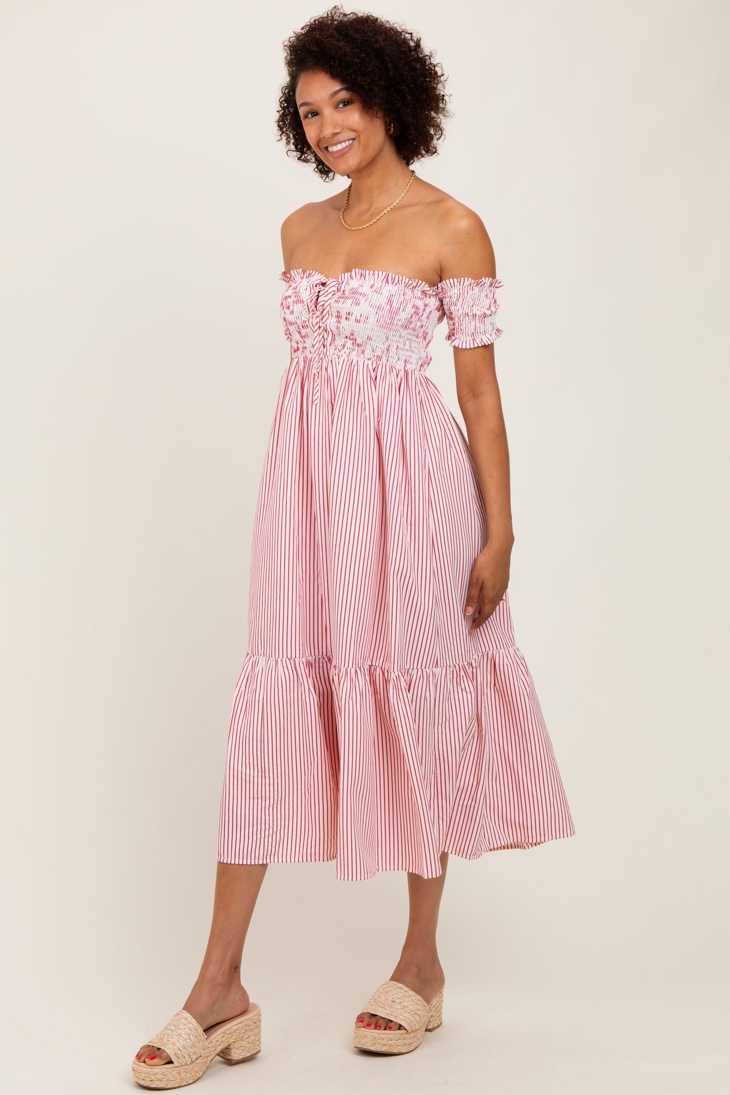 woman wearing a red and white striped off-the-shoulder dress with a tiered skirt and espadrille wedges
