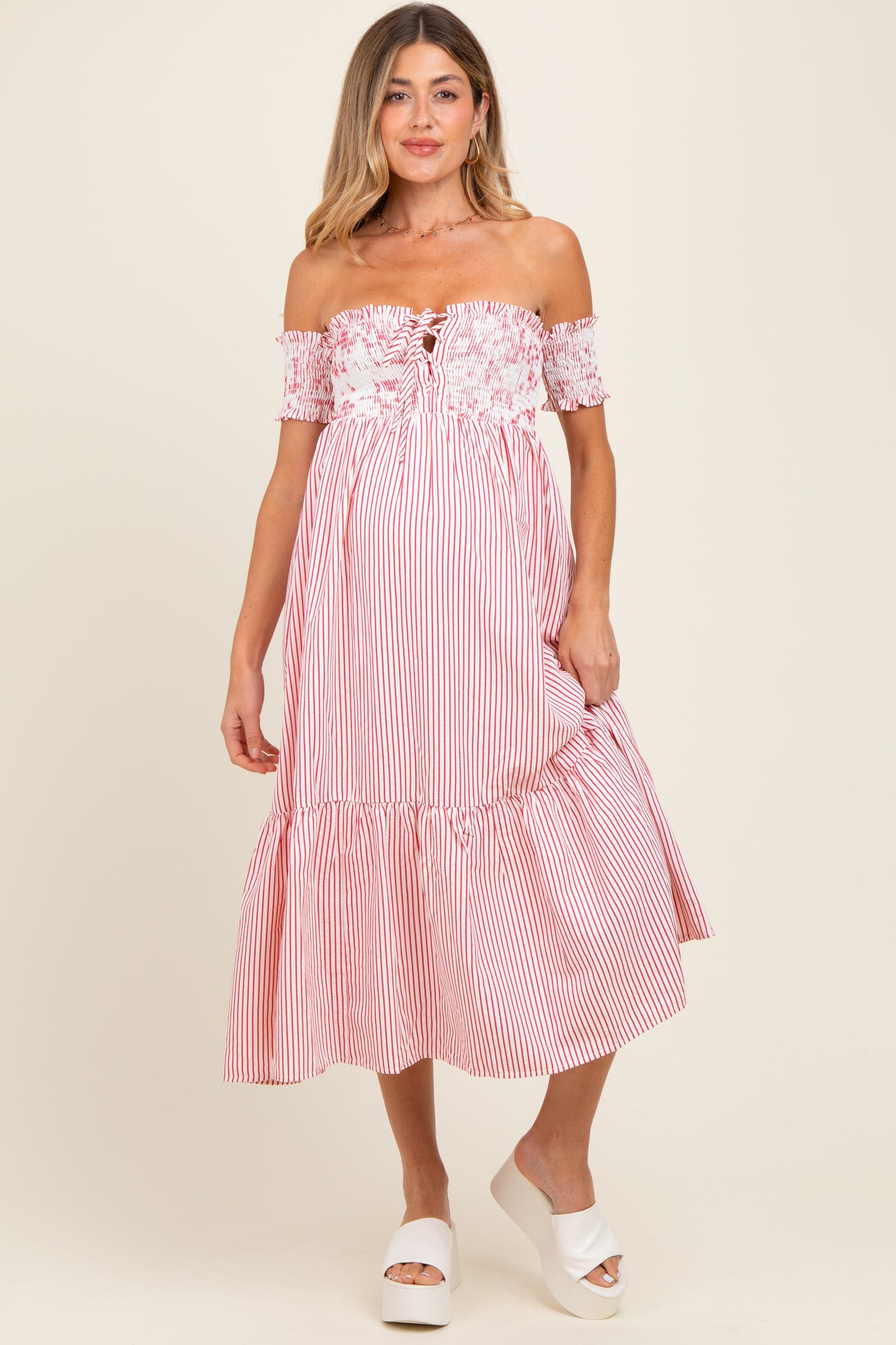 woman wearing a striped off-the-shoulder maternity dress with a ruffled hem and floral detail at the bodice