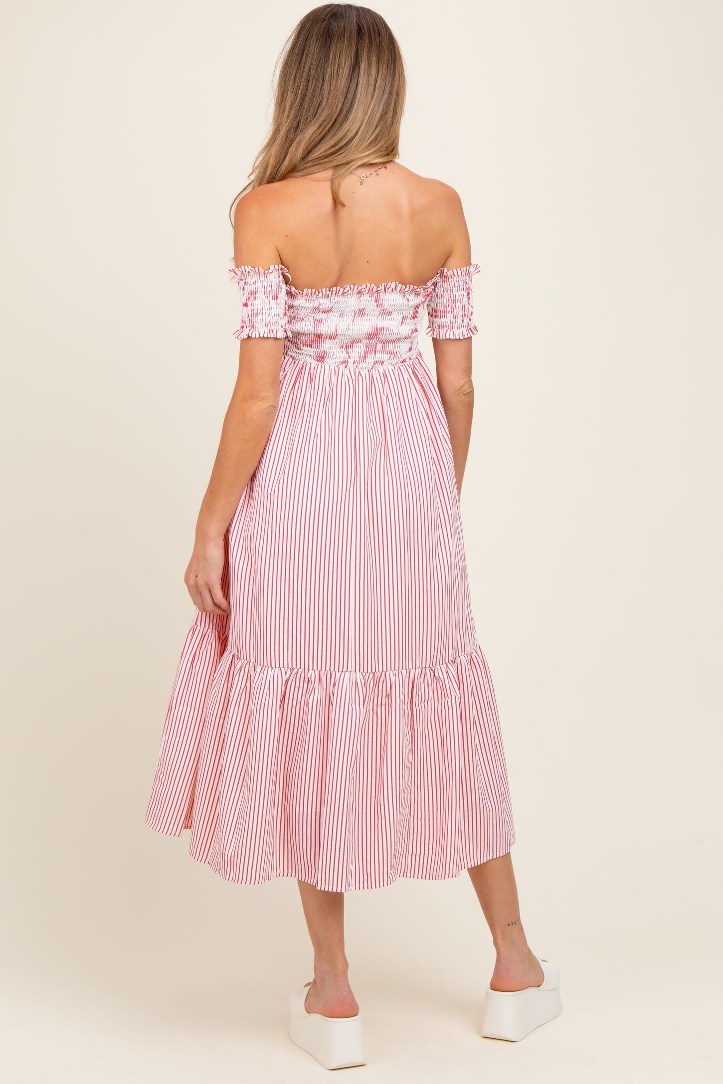 woman wearing a red and white striped off-the-shoulder maternity dress with a smocked bodice and tiered skirt