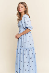 woman wearing a light blue maxi dress with floral embroidery and puff sleeves