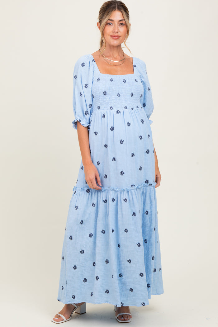woman wearing a light blue maternity maxi dress with square neckline and floral print, showcasing her baby bump