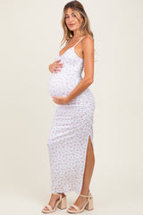 woman wearing a white floral print maternity maxi dress, showing her baby bump and posing with one hand on her belly