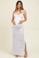 woman wearing a white floral maternity maxi dress with side slits and holding her baby bump