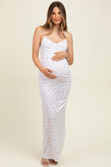 woman wearing a white floral maternity maxi dress and holding her baby bump