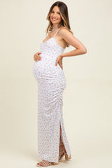 woman wearing a white floral maternity maxi dress with side ruching and a visible baby bump
