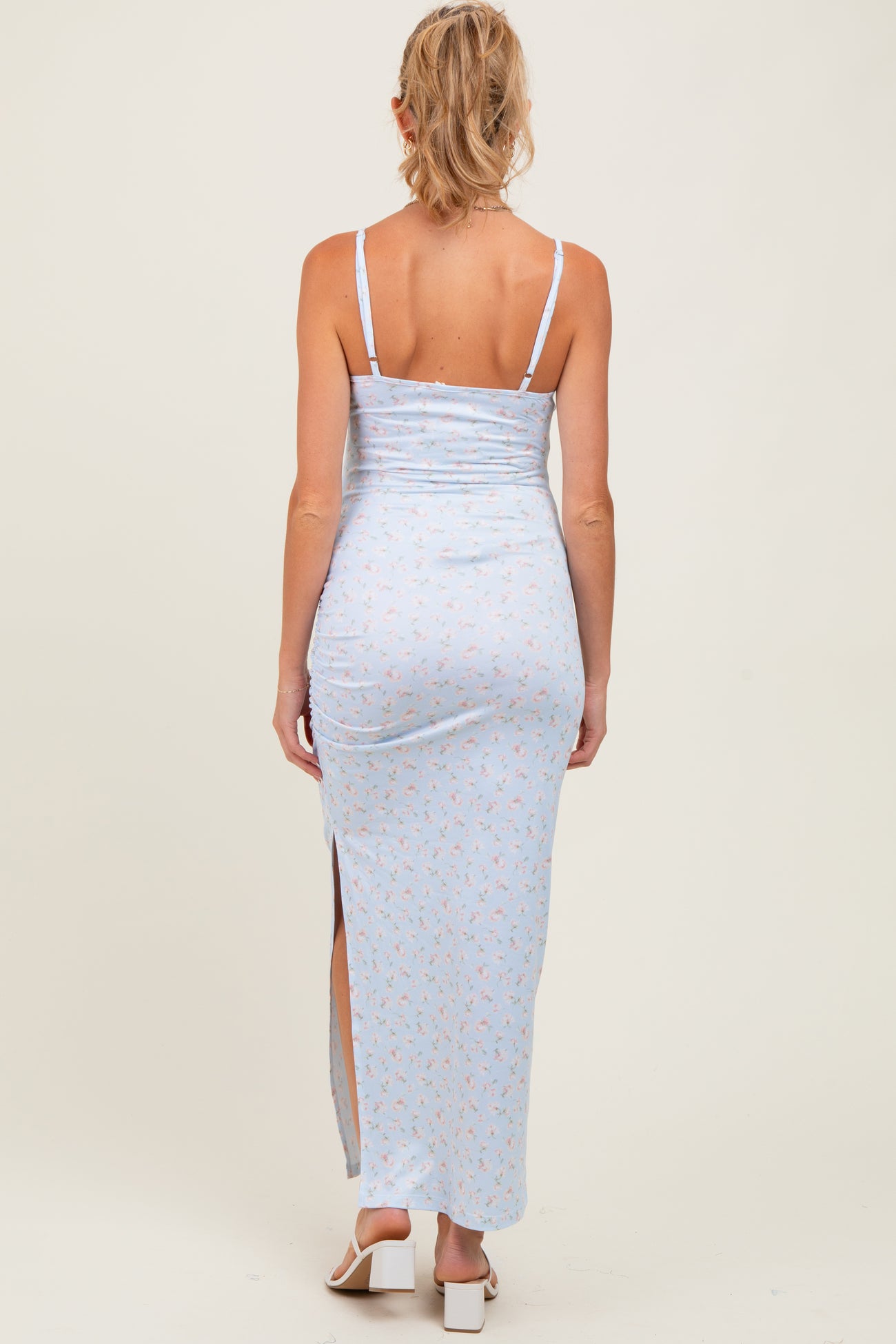 woman wearing a light blue floral maternity maxi dress with a side slit and adjustable straps, showing a baby bump