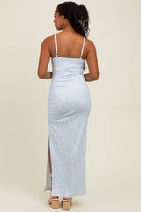 woman wearing a light blue floral print maxi dress with spaghetti straps and a side slit, viewed from the back