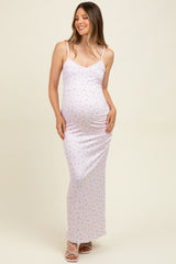 woman wearing a light pink floral maternity maxi dress with adjustable straps and a visible baby bump