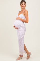 woman wearing a light purple floral maternity dress with ruching, holding her baby bump and smiling