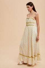 woman wearing a cream-colored floral maxi dress with thin straps and ruffle hem details