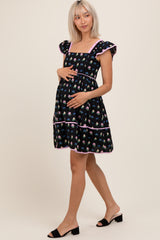 woman wearing a black floral maternity dress with ruffled sleeves and a visible baby bump