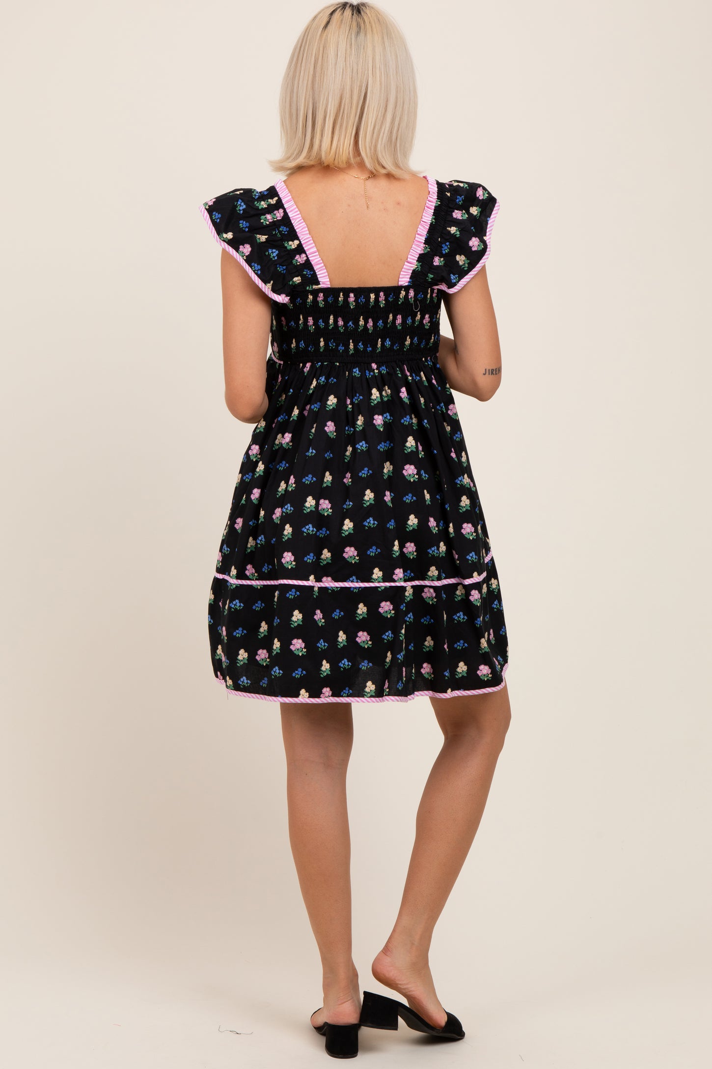 woman wearing a black floral maternity dress with ruffled sleeves and a smocked back detail