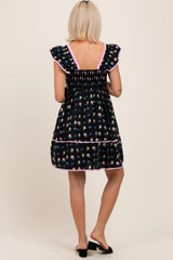 woman wearing a black floral maternity dress with ruffled sleeves and a smocked back detail