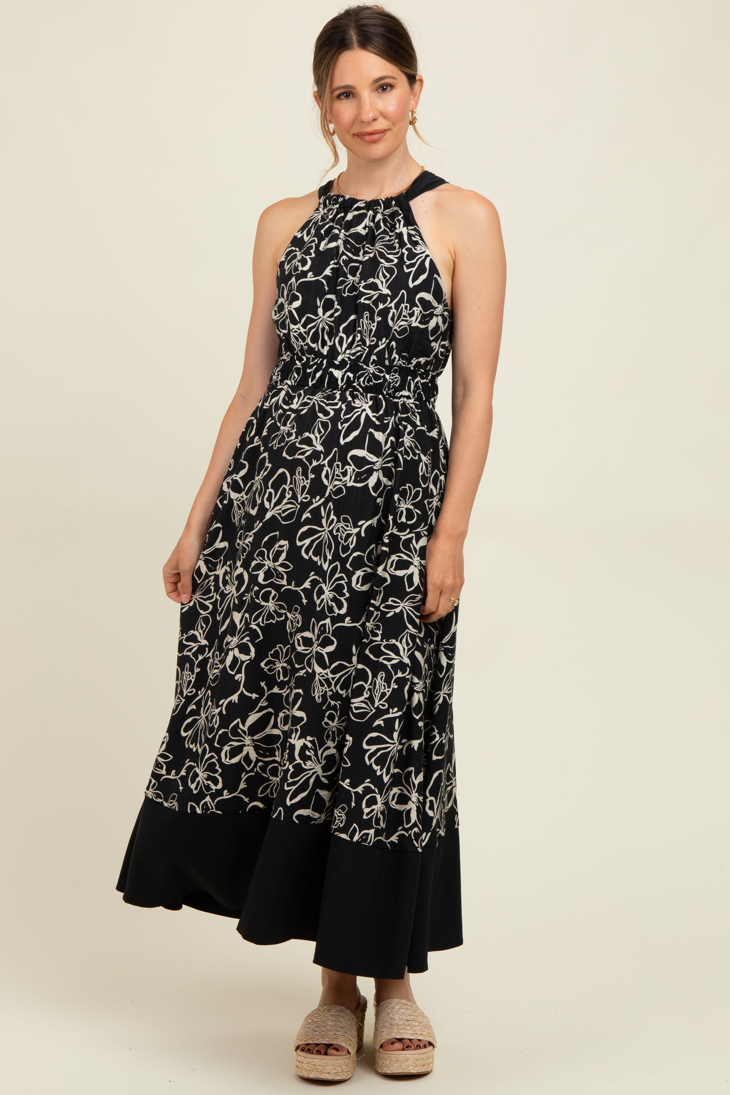 woman wearing a black and white floral maternity maxi dress with a halter neck and elastic waistband