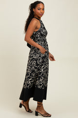 woman wearing a black floral print sleeveless maxi dress with a cinched waist and side pockets