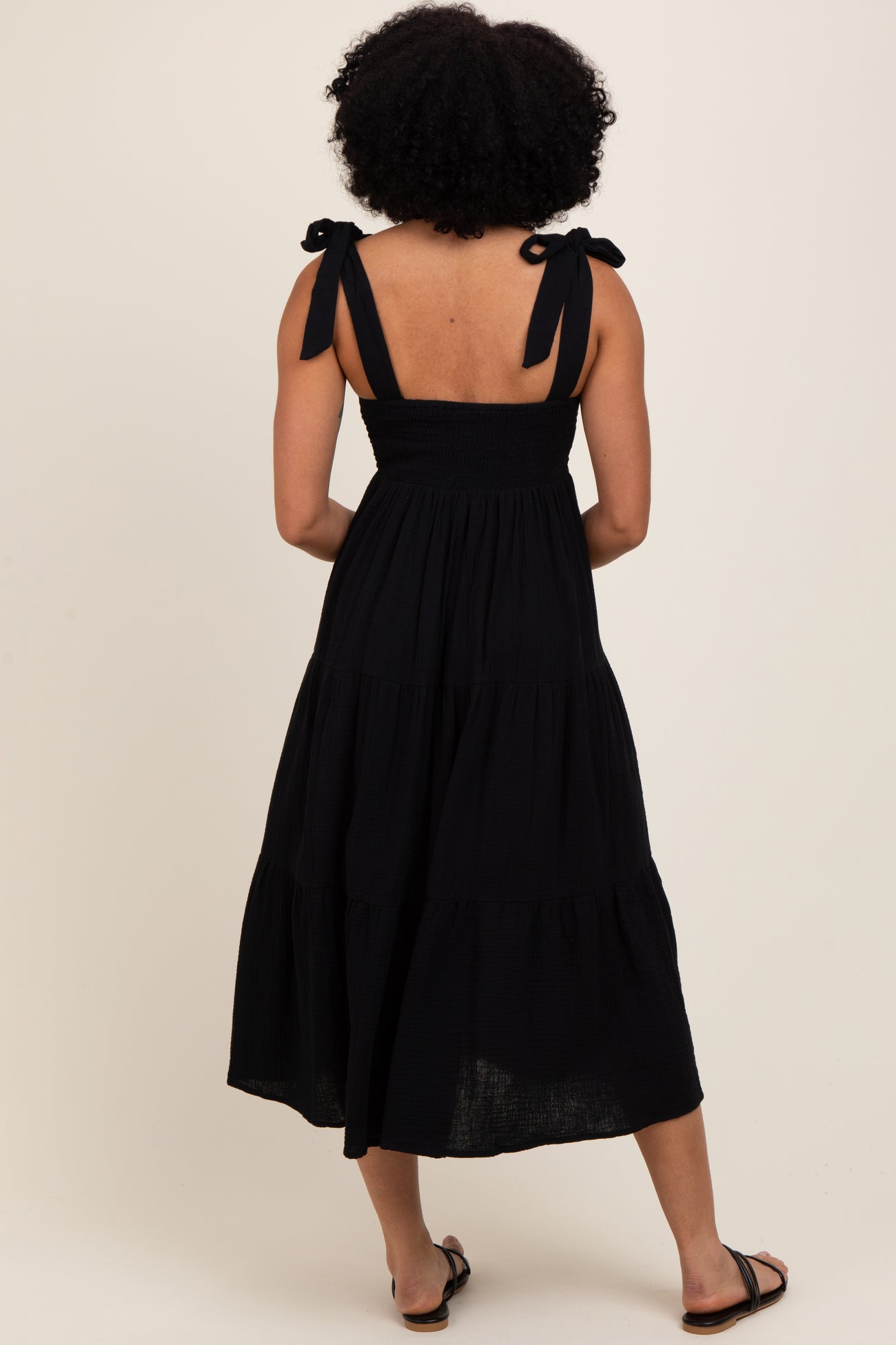 woman wearing a black tiered sundress with shoulder ties, seen from the back