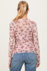 woman wearing a sheer pink long sleeve maternity top with floral print, showing her back and styling with high-waisted jeans