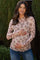 woman wearing a blush pink floral long sleeve maternity top and holding her baby bump