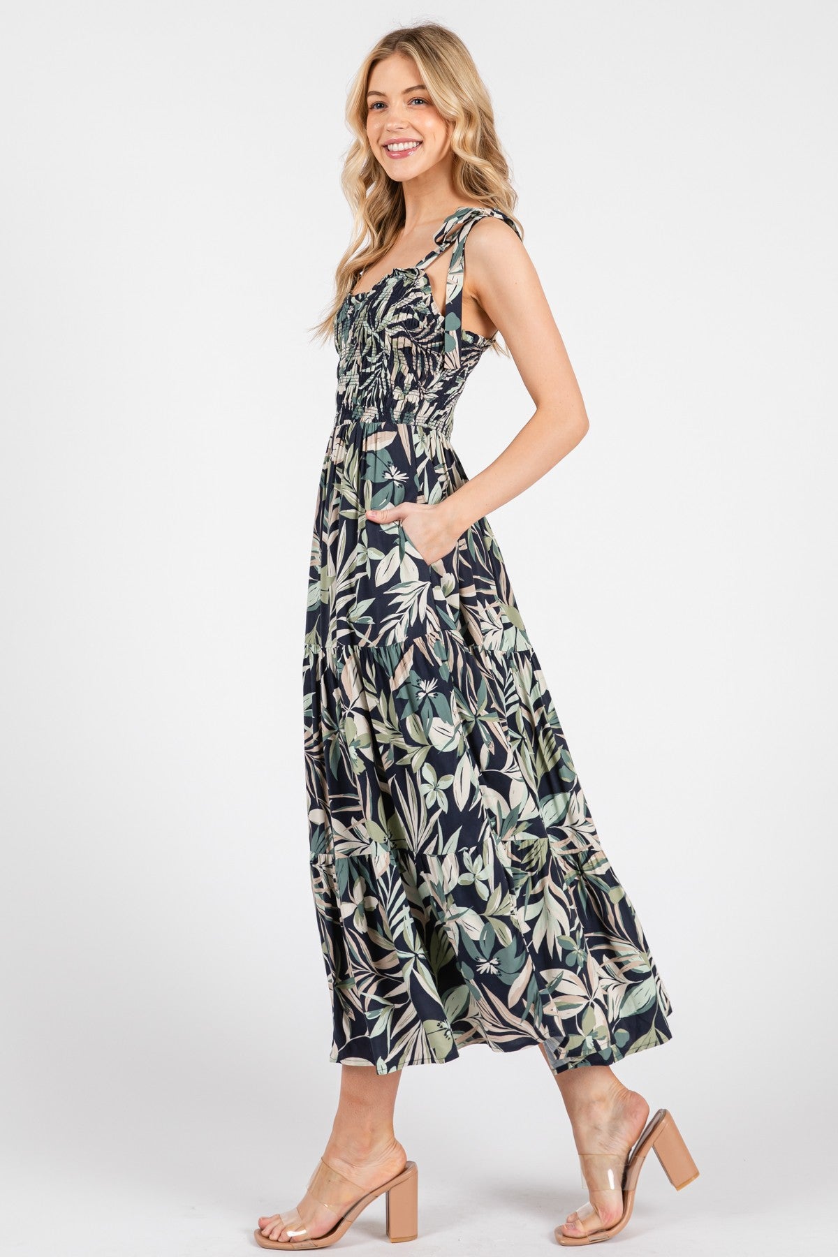 woman wearing a navy floral maxi dress with spaghetti straps and pockets, standing in profile