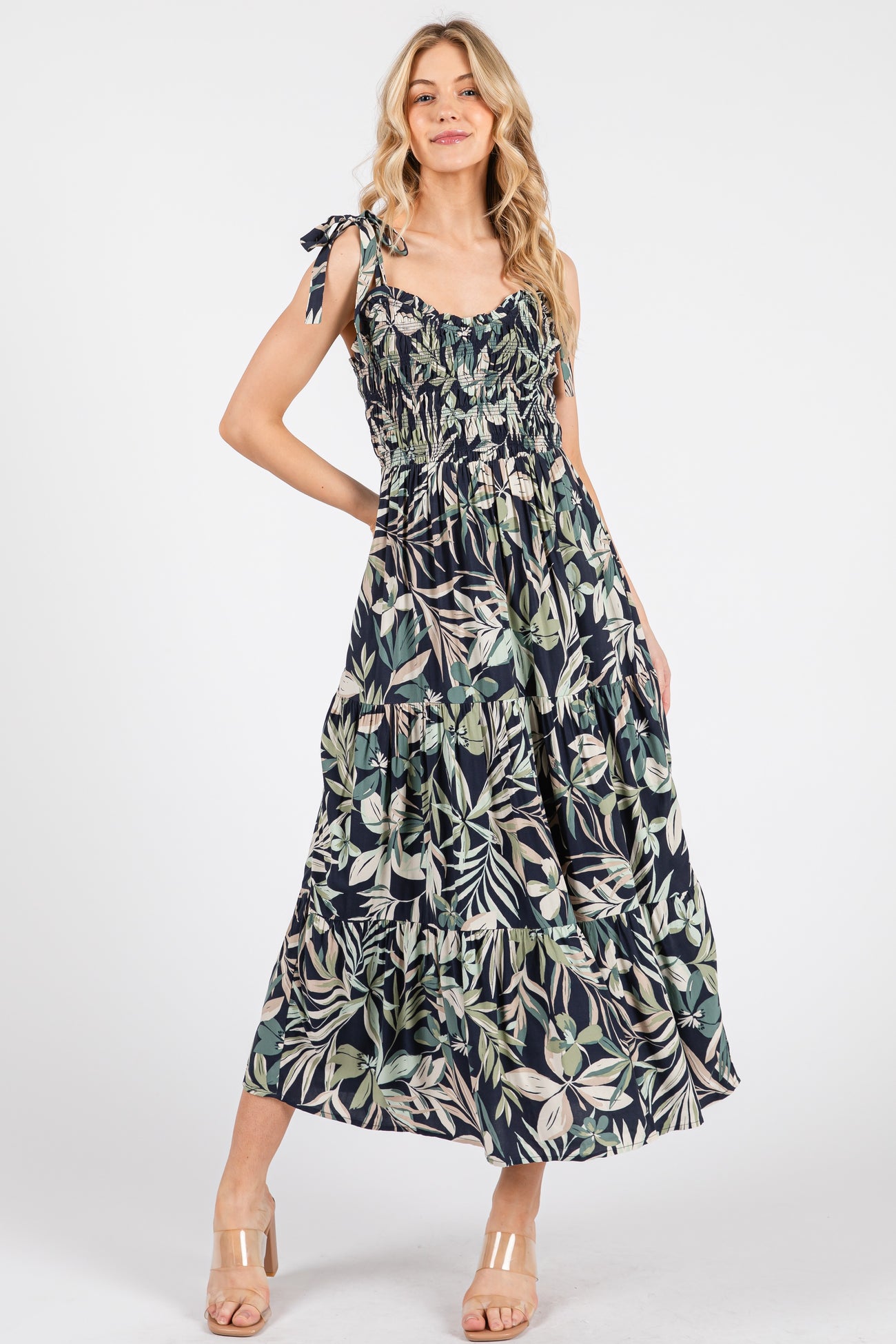 woman wearing a floral print maxi dress with tie straps and smocked bodice, standing against a white background