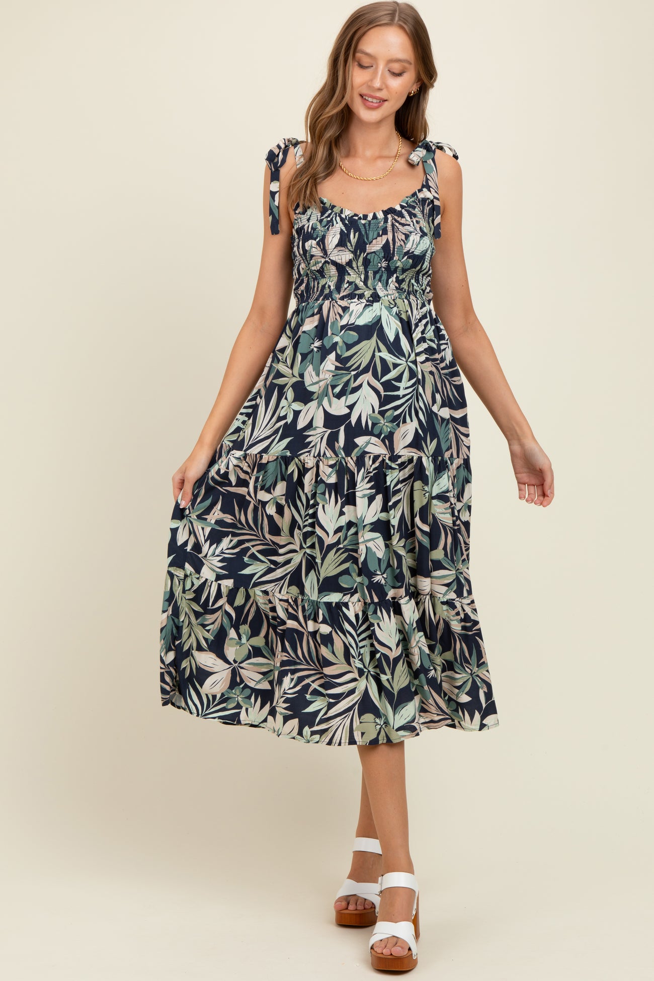 woman wearing a navy blue floral maternity maxi dress with tie shoulder straps and a tiered skirt
