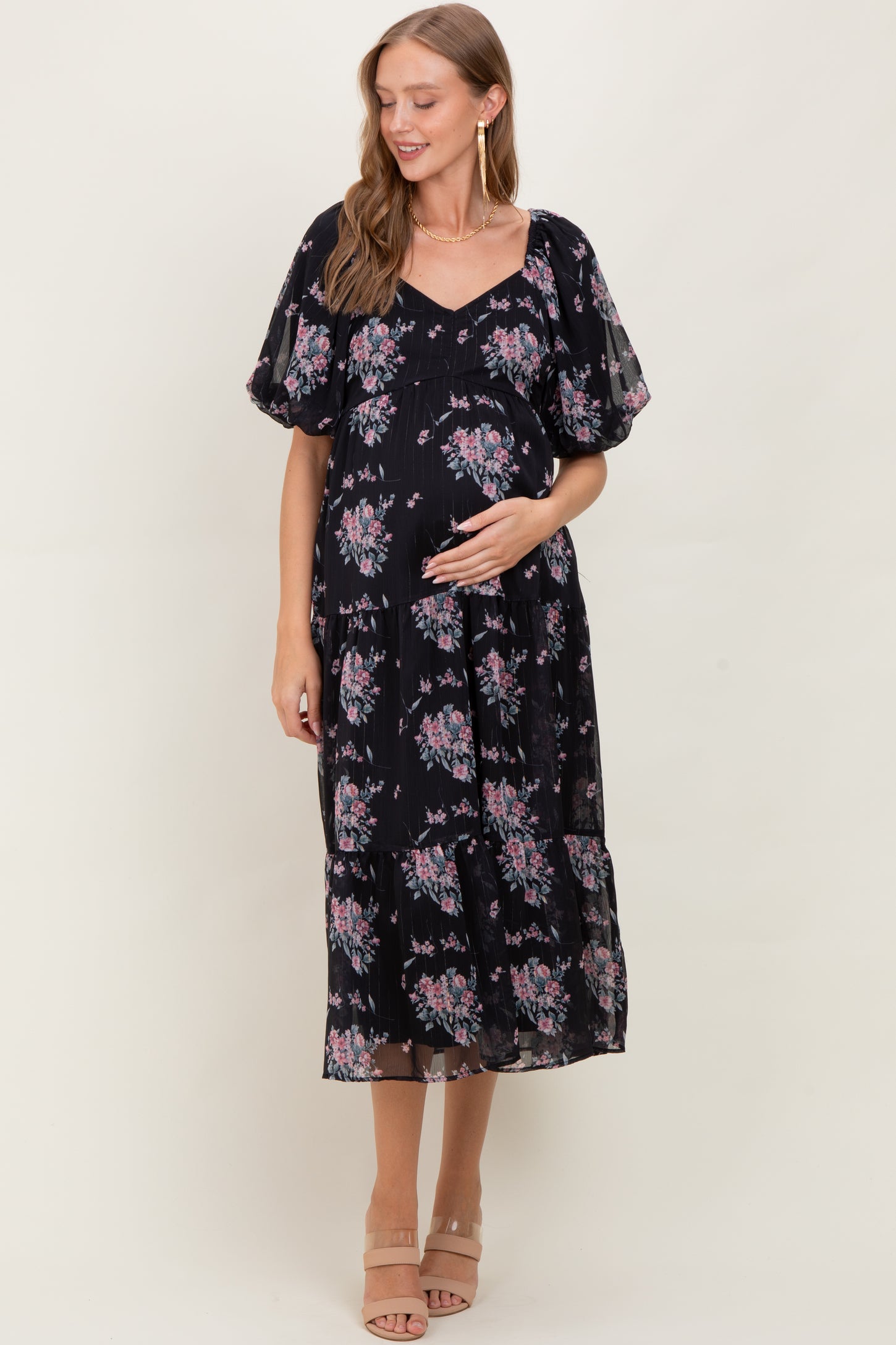 woman wearing a black floral print maternity maxi dress with puff sleeves and a visible baby bump