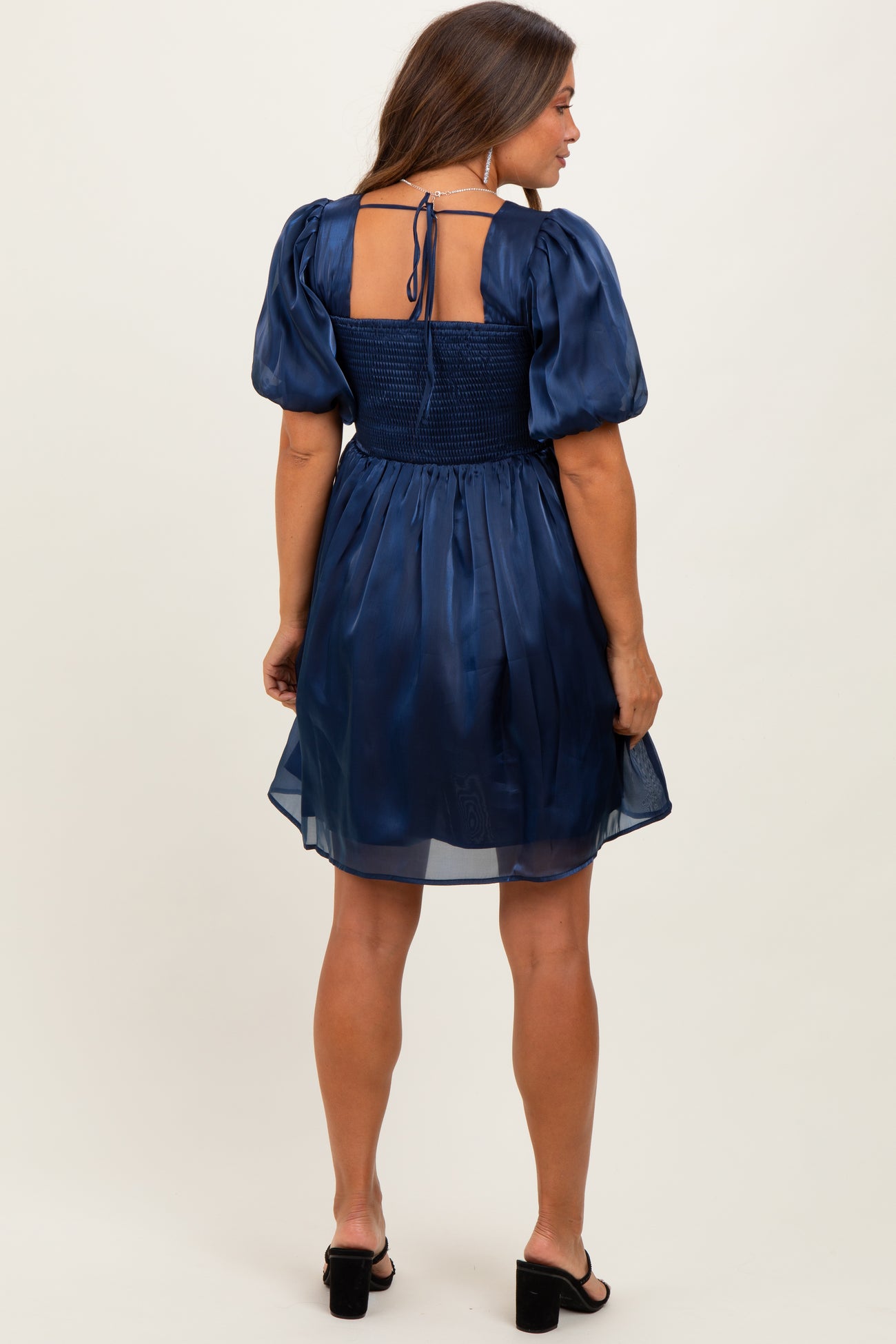 woman wearing a navy blue maternity dress with puff sleeves and a smocked back detail