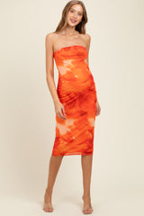 woman wearing a strapless orange watercolor print maternity dress with a fitted silhouette and a knee-length hem