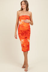 woman wearing a strapless orange and white tie-dye maternity dress and holding her baby bump