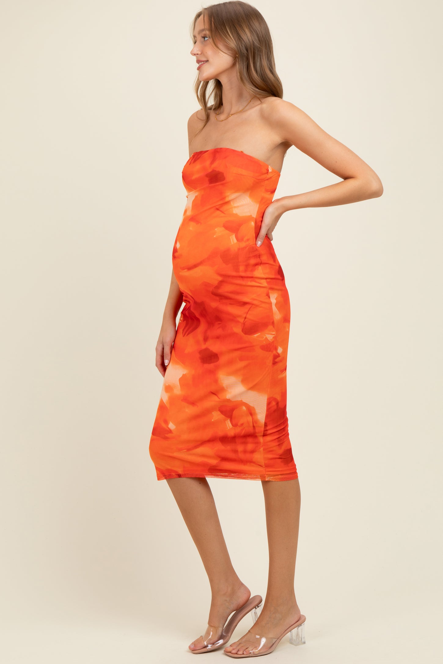 woman wearing a strapless orange floral maternity dress that shows off her baby bump