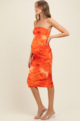 woman wearing a strapless orange floral maternity dress that shows off her baby bump
