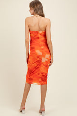 woman wearing a strapless orange floral maternity dress, showcasing a form-fitting silhouette and mid-length cut