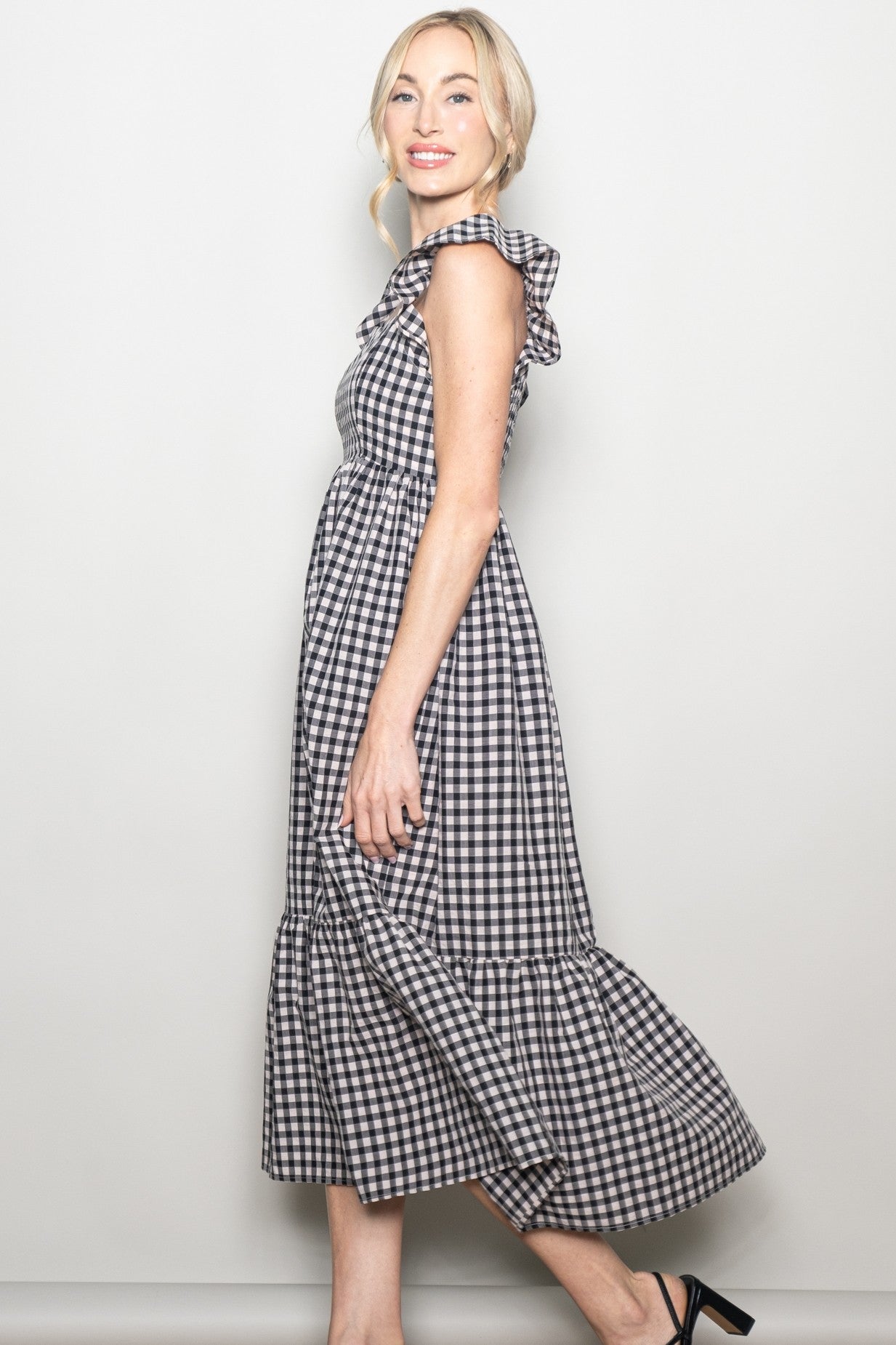 woman wearing a black and white gingham maxi dress with ruffle details and a tiered skirt