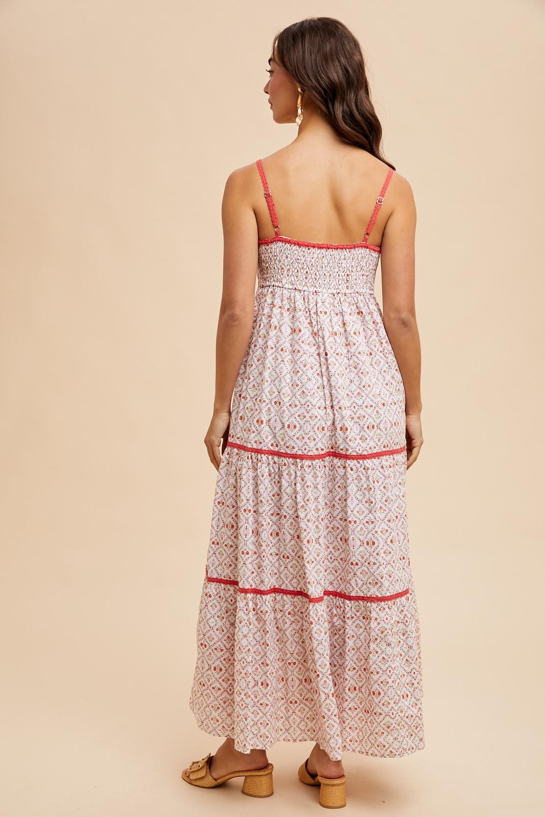 woman wearing a white patterned maxi dress with smocked bodice and tiered skirt, standing with her back to the camera