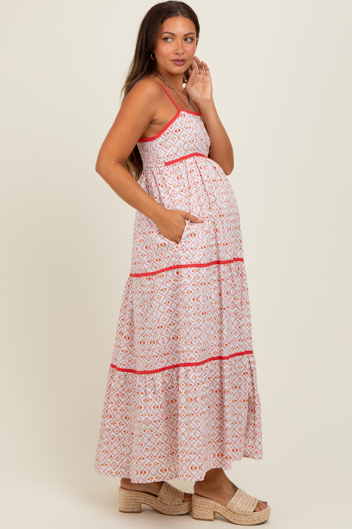woman wearing a pink and white patterned maternity maxi dress with pockets and a visible baby bump