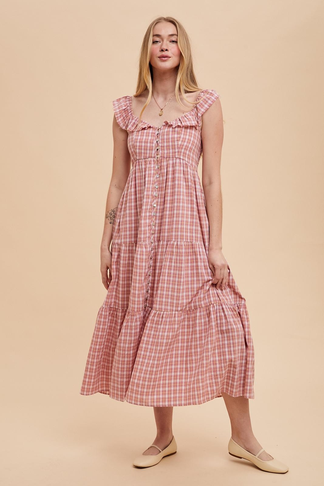 woman wearing a pink and white checked midi dress with ruffled straps and button details