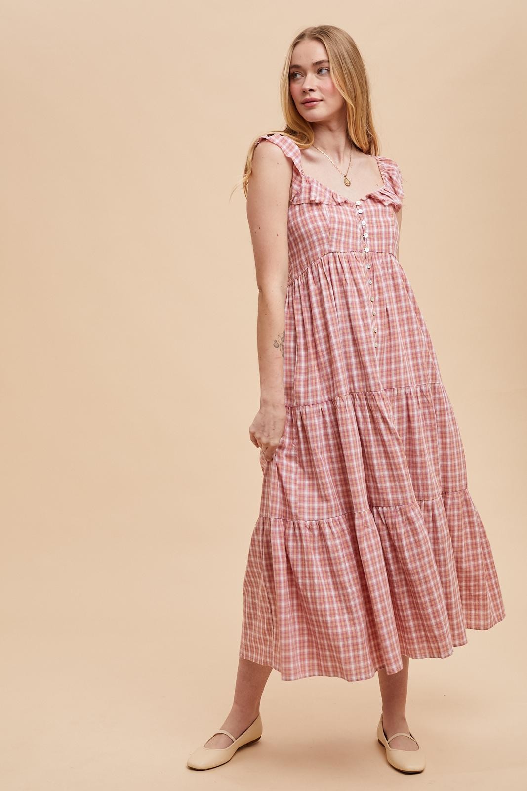 woman wearing a pink and white checked maxi dress with ruffle straps and button details