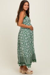 woman wearing a green bohemian print maternity maxi dress and holding her baby bump