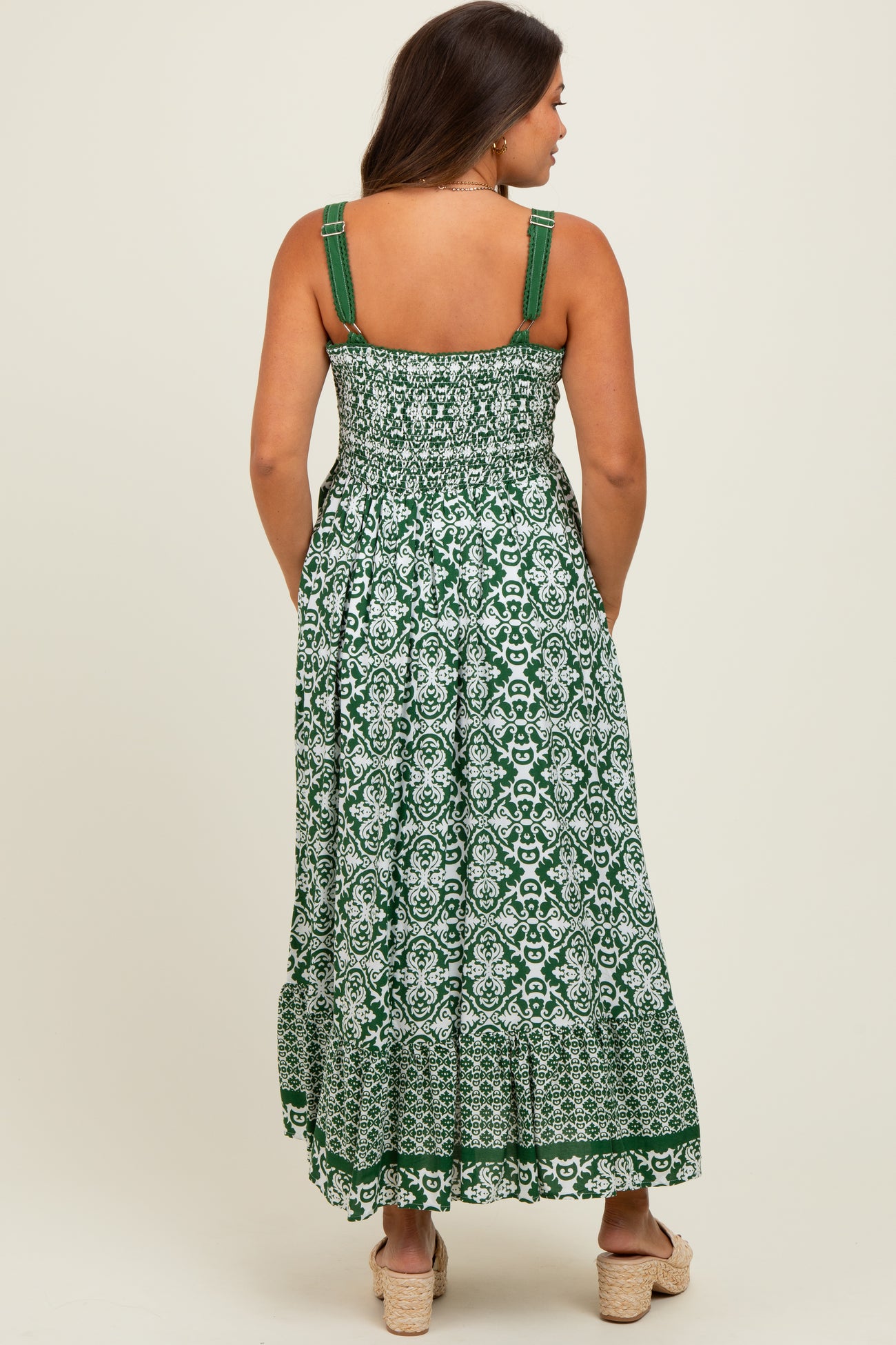 woman wearing a green and white patterned maternity maxi dress with adjustable straps and a smocked back