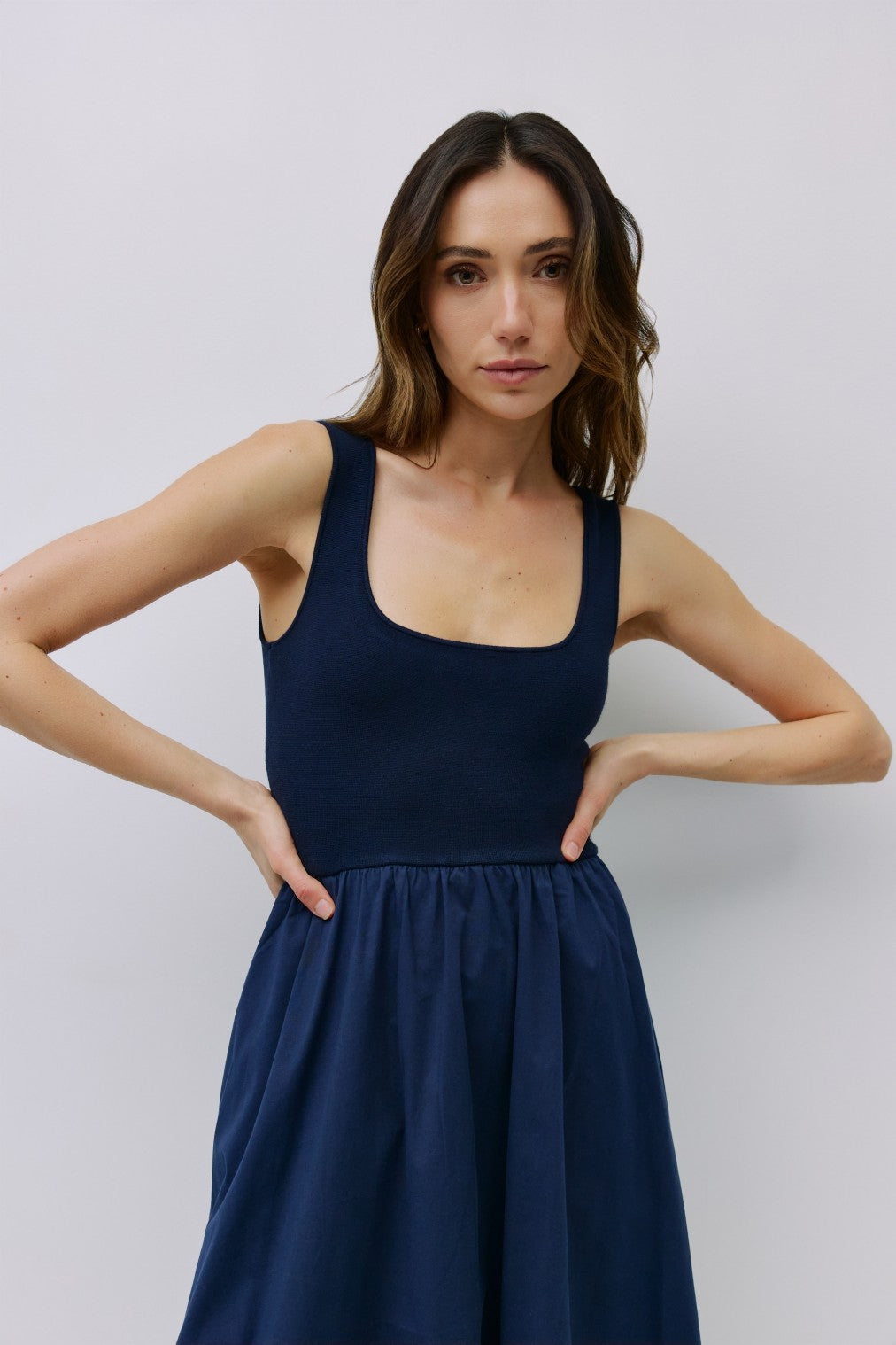 woman wearing a navy blue sleeveless dress with a fitted bodice and a flared skirt